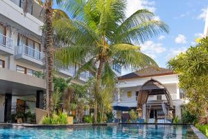 沙努尔阿维安华美伦酒店 的棕榈树建筑前的游泳池