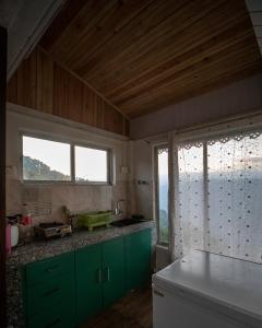 大吉岭MiakaHillsDarjeeling的一个带绿色橱柜和大窗户的厨房
