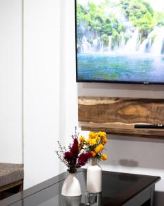 大吉岭MiakaHillsDarjeeling的两张白色花瓶,桌子上放着鲜花,配有电视