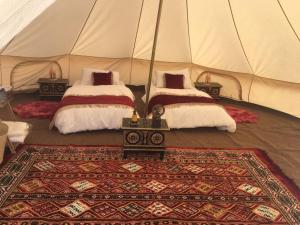 MuntaribDesert Moments Glamping - full privacy的帐篷内的两张床,铺有地毯