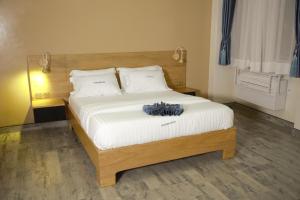 坎帕拉Victoria Mews Hotel的一间卧室配有一张带白色床单的大床