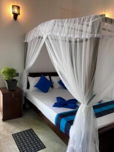 米瑞莎Bisandu guesthouse的一间卧室配有一张带蓝色枕头的天蓬床