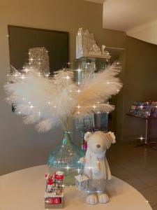 艾格-莫尔特艾格莫特运河酒店的一只泰迪熊坐在一个花瓶边,上面有羽毛