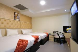 新加坡Sandpiper Hotel Singapore的酒店客房设有两张床和电视。