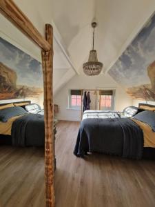 福尔特赫伊曾Bed & Breakfast Hoeve Happiness的墙上挂有绘画的客房内的两张床