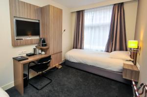 阿姆斯特丹Hotel Fine Harmony的酒店客房配有一张床、一张书桌和一台电视。
