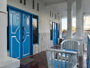 吉利特拉旺安The House Hostel的门廊设有蓝色门和白色椅子