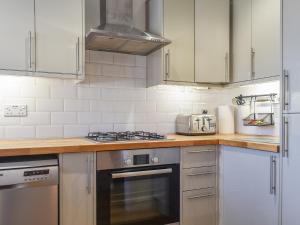 Saint HelensCoed Faen的厨房配有白色橱柜和炉灶烤箱。