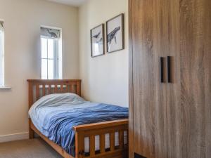 Saint HelensCoed Faen的一间卧室配有一张床和一个木制衣柜