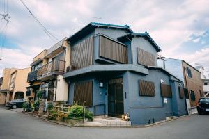 京都Tofukuji Saku Inn（东福寺咲く宿）的蓝色的建筑,前面有一只狗