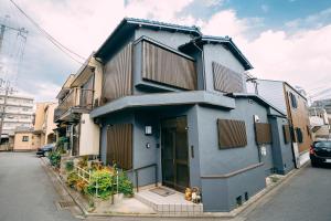 京都Tofukuji Saku Inn（东福寺咲く宿）的蓝色的房子,前面有两只狗
