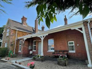 斯内蒂瑟姆The Old Station, Station House, Snettisham Norfolk的砖房,前面有长凳