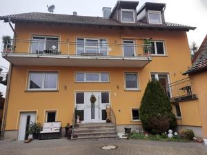 GaukönigshofenFerienwohnung Dürr的黄色的房屋,设有楼梯和阳台