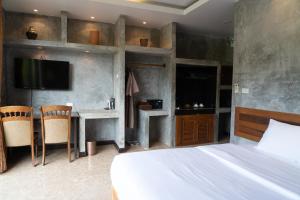 他朗Anodard Phuket, Nai Yang Beach的一间卧室配有一张床、一张书桌和一台电视。