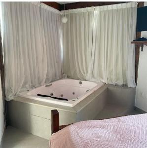 新利马Pousada Canto da Lua的带浴缸的带窗帘和床的房间