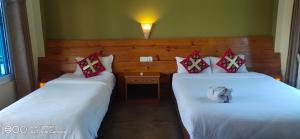 索拉哈Hotel hornbill的配有白色床单和红色枕头的酒店客房内的两张床