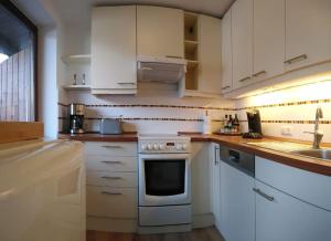 格门德蒂格斯Wohnung direkt am Tegernsee mit XL-Terrasse的厨房配有白色橱柜和炉灶烤箱。