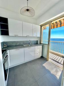 芒通« LA SUITE »Superbe appartement NEUF, Front de mer的一间厨房,配有白色的橱柜,享有海景