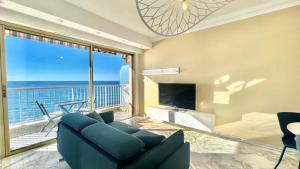 芒通« LA SUITE »Superbe appartement NEUF, Front de mer的客厅配有蓝色沙发,享有海景