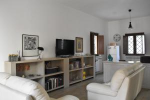 拉奎拉Le Radici Home的客厅配有两把白色椅子和电视
