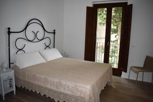 拉奎拉Le Radici Home的一间卧室配有一张带床头板的床和两个窗户