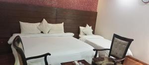 卡拉奇Hira Guest House的两张位于酒店客房的床 - 带椅子
