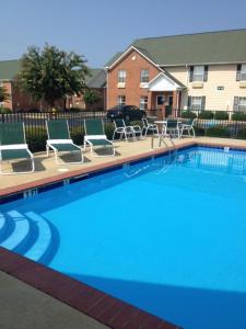 普拉特维尔InTown Suites Extended Stay Prattville AL的一个带躺椅的游泳池以及一座房子
