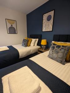 阿德尔斯通3 Bed 2 Lounge House up to 40pc off Monthly in Addlestone by Angel and Ken Serviced Accommodation Great Value for Long-term Stay的蓝色墙壁客房的两张床