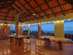 埃斯孔迪多港Nopalero Suites Hostel的餐厅设有木桌、椅子和窗户。