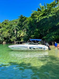 安格拉杜斯雷斯Passeios de lancha em Angra dos Reis的坐在海滩旁的水面上的船