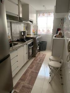 戈亚尼亚Apto com conforto que você precisa.的厨房配有白色橱柜、水槽和椅子