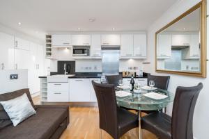伦敦Camden Town Apartment的厨房以及带玻璃桌和椅子的客厅。