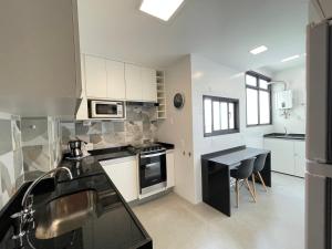 里约热内卢Ipanema - Rainha Elizabeth - 2 Quartos的厨房配有白色橱柜和黑色台面