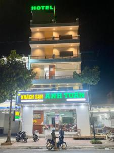 Bạc LiêuKhách sạn Anh Tuấn的两人在酒店门前骑摩托车