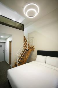 釜山Haeundae Blue Story Hotel的卧室配有白色的床和楼梯。