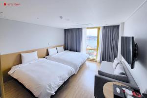 丽水市Hotel Kenny Yeosu的酒店客房设有两张床和一台平面电视。