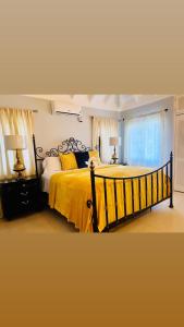 PrioryIsle Be Back Villa的一间卧室配有一张带黄色床单的大床和窗户。
