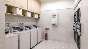 户田市Toyoko Inn Kita-toda-eki Higashi-guchi的洗衣房配有一排洗衣机和烘干机