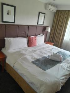哈里史密斯Protea Hotel by Marriott Harrismith Montrose的一张配有白色床单和红色枕头的大床