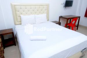 PampangFortuner Homestay Syariah Makassar Mitra RedDoorz的卧室配有白色的床和桌子