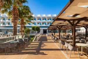 法里拉基蓝色海滩度假酒店的一个带桌椅的户外庭院,棕榈树