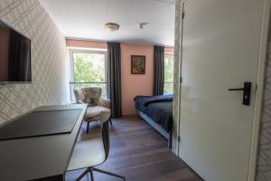 巴特纽维斯Hotel Leeuwerik的一间卧室配有一张床、一张桌子和一把椅子