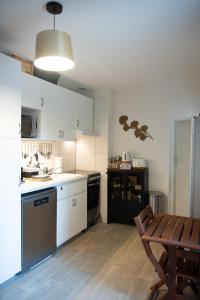 莱桑德利Les Gites By Carpe Diem的厨房铺有木地板,配有白色橱柜和桌子。