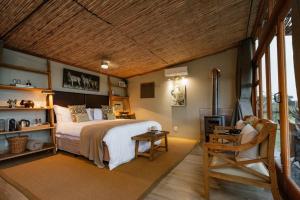 纳姆比提动物保护区Cheetah Ridge Lodge的一间卧室配有一张大床和一把椅子