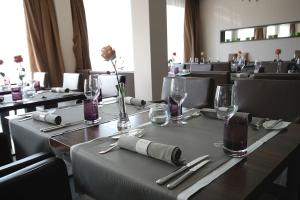 比蒂希海姆-比辛根Hotel Eberhards am Wasser的用餐室配有带玻璃杯和银器的桌子