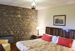 科伦加Hotel Los Caspios的一间卧室设有石墙和一张带红色枕头的床。