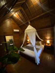 BanjarangkanKubu Bakas Guest House - CHSE Certified的一间卧室配有一张带蚊帐的床