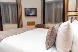 贝尔法斯特塔拉旅馆的一间卧室配有一张带枕头的白色床和电视。