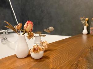 迪塞L'Autre Rivière - Chambres d'hôtes的木桌上三个白色花瓶,花朵花