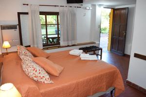 诺诺Los Sauces Posada的一间卧室配有带橙色床单的床和窗户。